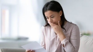 Tenant looking concerned while reading a letter, reflecting on the implications of breaking a lease and its impact on rental history.
