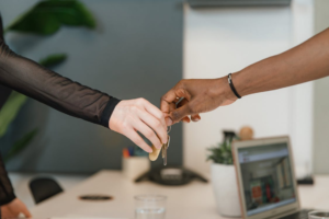 Hands exchanging keys in a rental property setting, symbolizing tenant selection and background checks and screening.