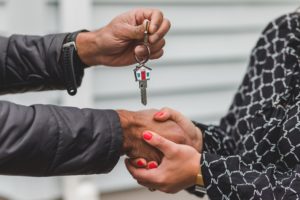 Hands exchanging keys, symbolizing successful tenant onboarding in property management services.