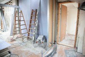 Interior renovation space with ladders, construction materials, and an open doorway, illustrating property upgrade process for older homes in Palm Beach.