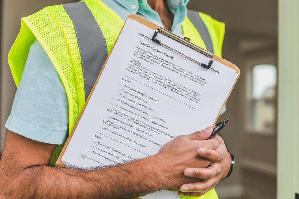 Property inspector holding a checklist in a safety vest, emphasizing the importance of regular property inspections for effective property management.