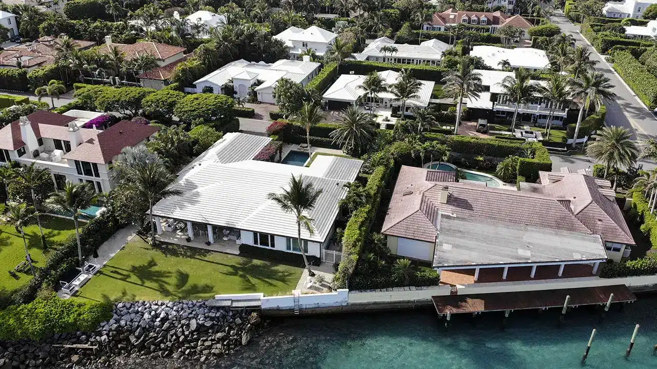 Aerial view of luxury homes in West Palm Beach, showcasing landscaped gardens, swimming pools, and proximity to water, emphasizing the region's upscale rental market dynamics.