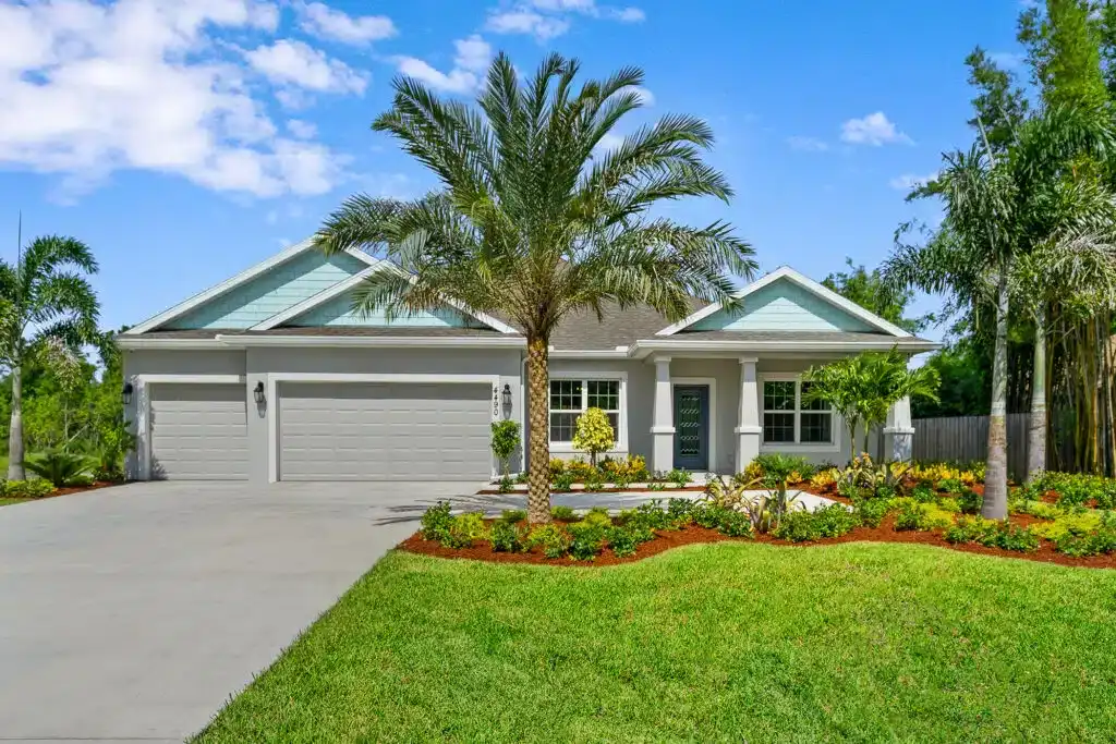 Modern Florida home with palm trees, manicured lawn, and bright blue sky in Port Saint Lucie new housing community.