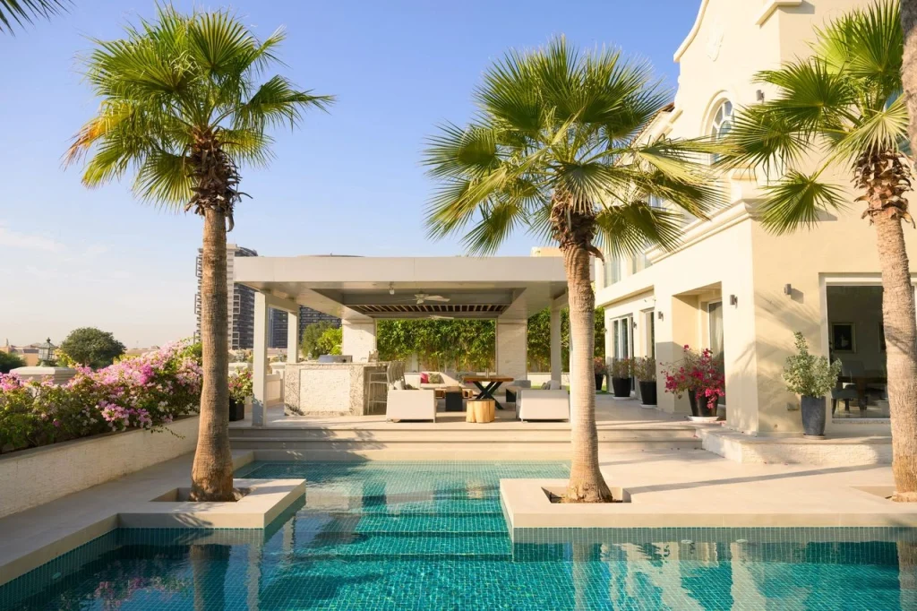 Luxury property with a swimming pool, palm trees, and outdoor seating area, showcasing a modern design ideal for rental investment in West Palm Beach.
